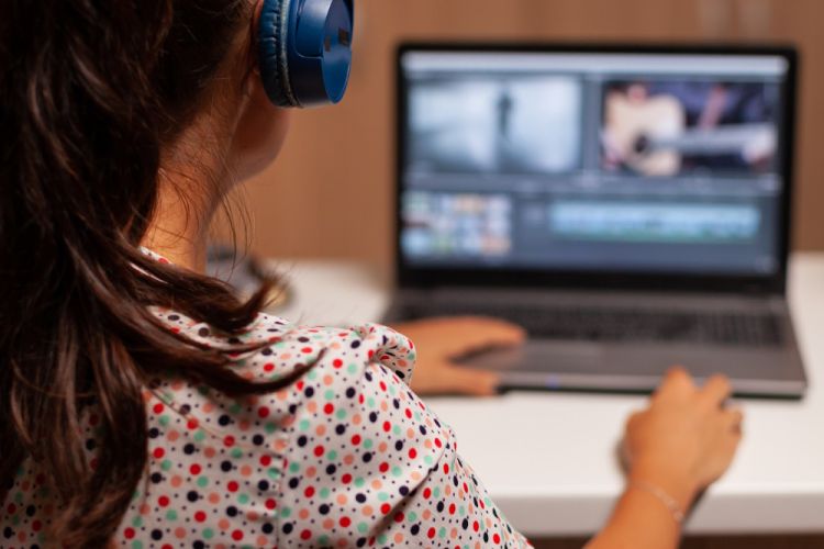 mujer escuchando y editando videos en su computadora