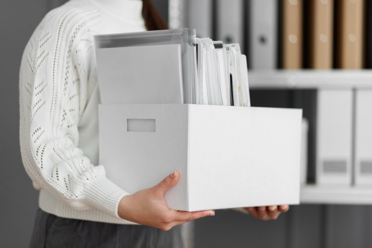 Hombre tomando una caja de archivos con documentos dentro